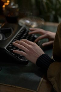 Hands of an adult typing on a vintage typewriter, set indoors with classic tones.