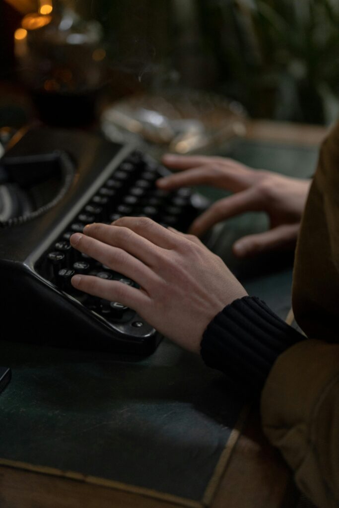 Hands of an adult typing on a vintage typewriter, set indoors with classic tones.
