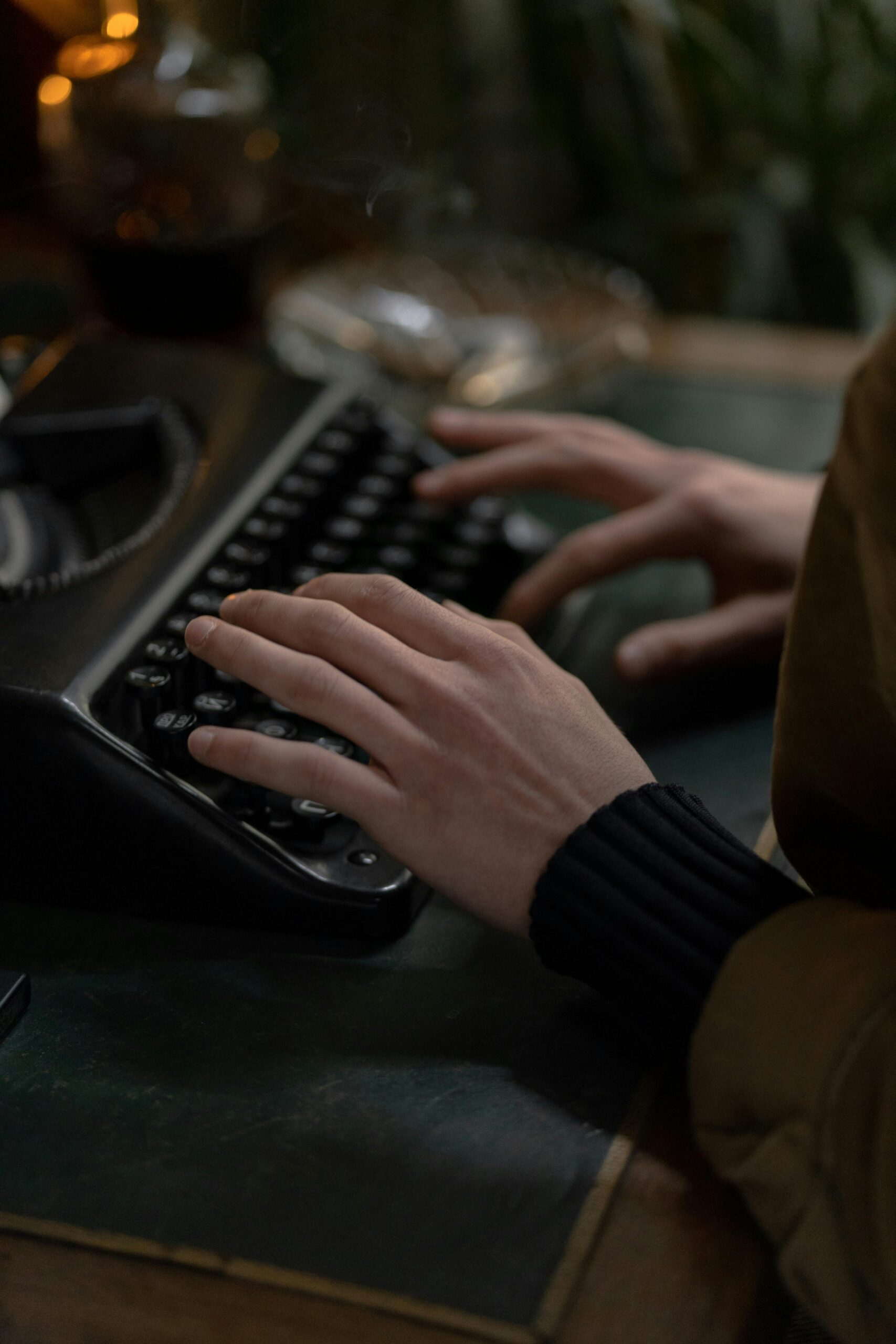 Hands of an adult typing on a vintage typewriter, set indoors with classic tones.